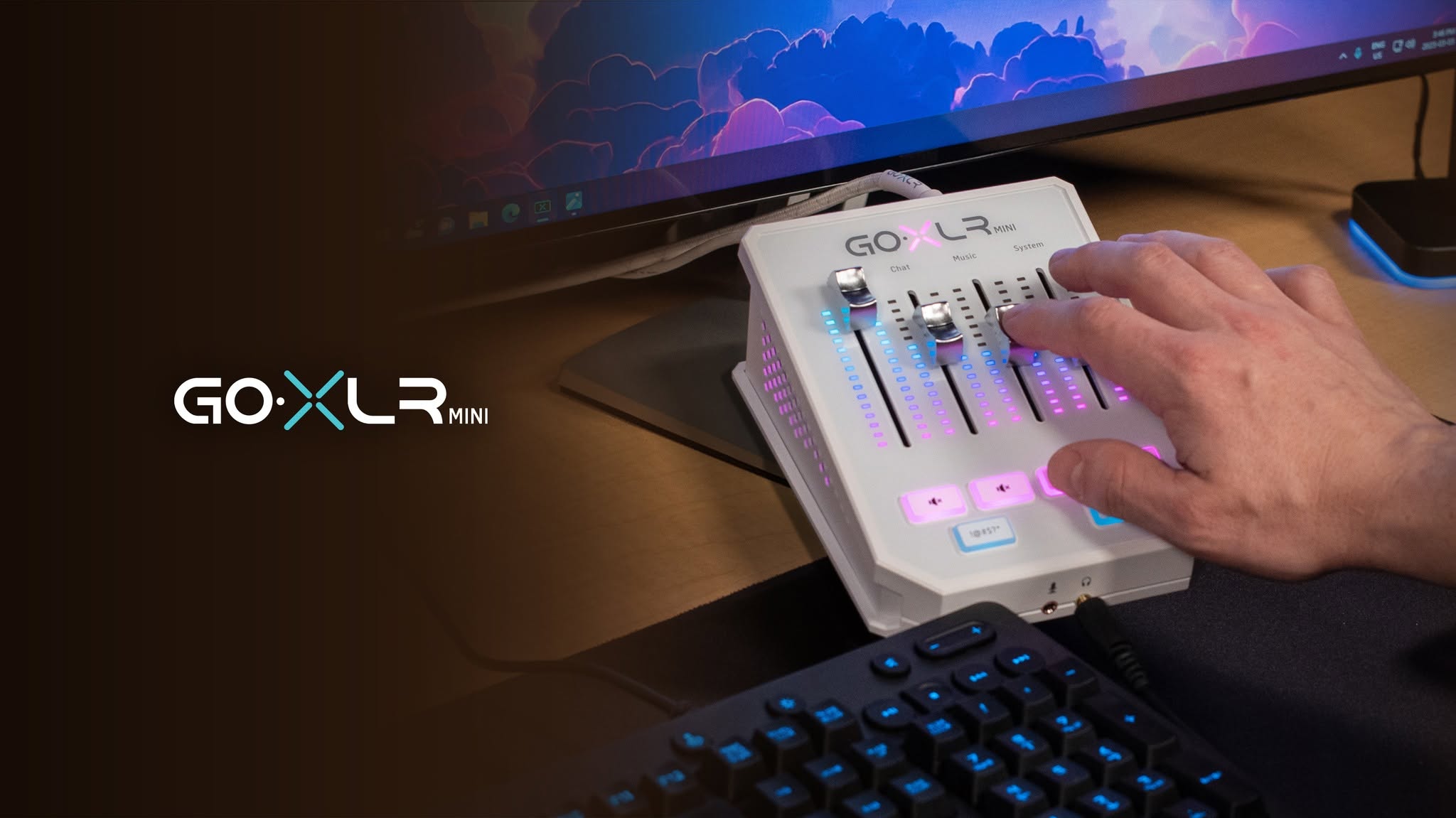 A white GoXLR Mini on a desk with its faders lit cyan and pink.